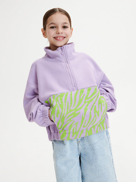 Child wearing a purple and green zebra patterned sweater on a white background