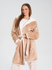 Woman wearing a beige robe with white trim on a plain background