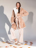 Woman wearing a beige robe and checkered pants standing on a light gray background with autumn leaves at the bottom.