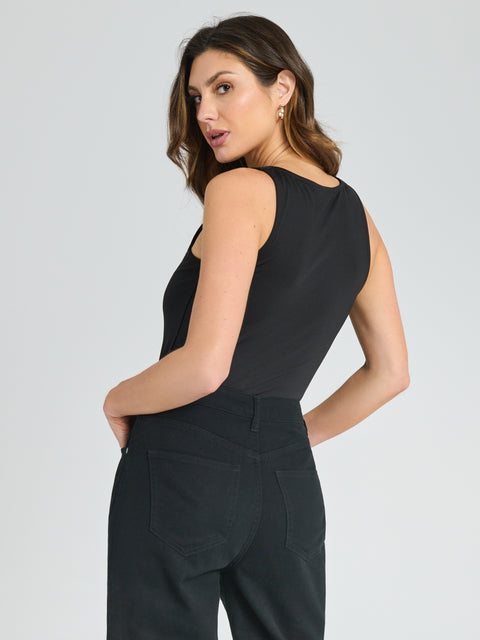Woman wearing a black sleeveless top and pants on a light gray background