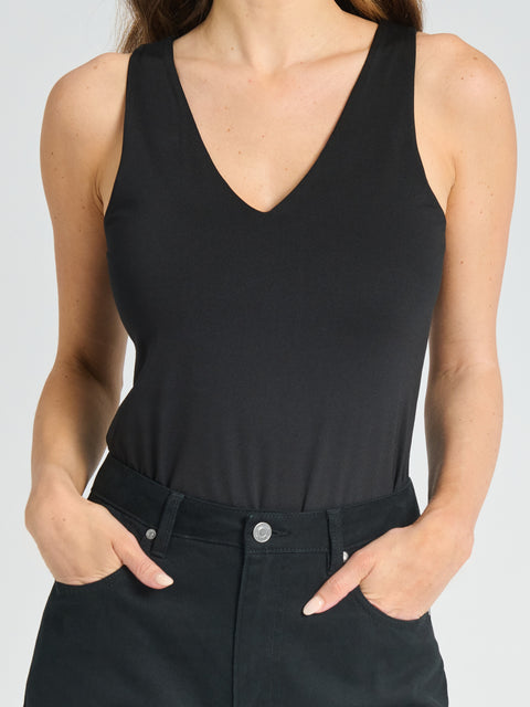 Person wearing a black sleeveless top and black pants on a light gray background