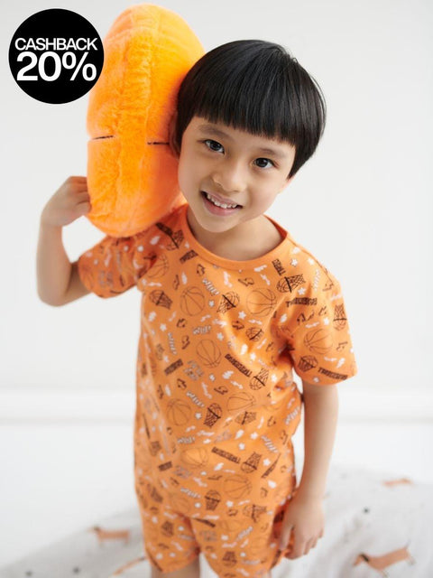 Child wearing an orange pajama set with a pattern, holding an orange toy on a white background