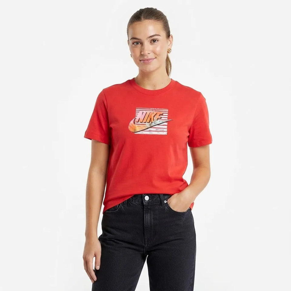 A woman modeling a red short-sleeve crewneck t-shirt with a retro Nike graphic on the chest, paired with black jeans, against a plain white background.