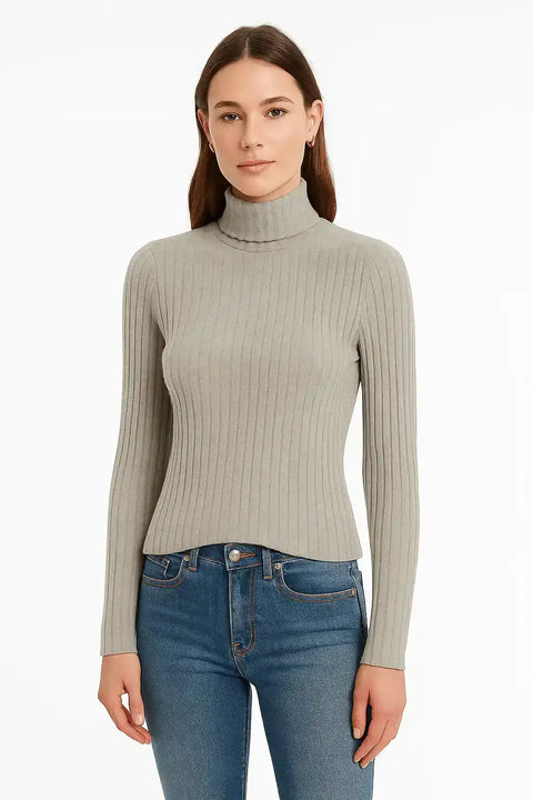 Woman wearing a gray ribbed turtleneck sweater and blue jeans on a white background