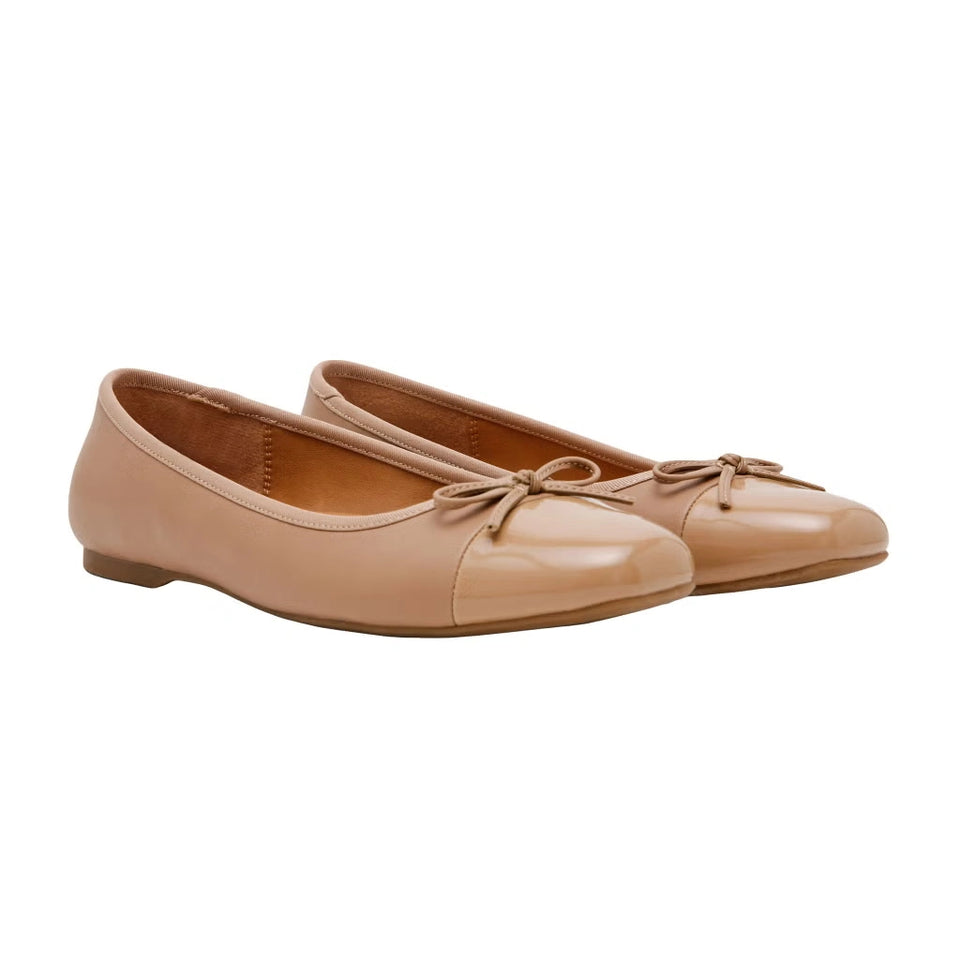 Pair of beige ballet flats with a bow on a white background