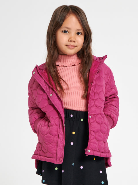 Young girl wearing a pink quilted jacket over a pink sweater on a white background
