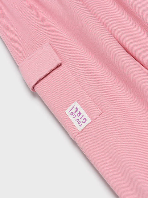 Close-up of a pink fabric with a brand label on a light gray background
