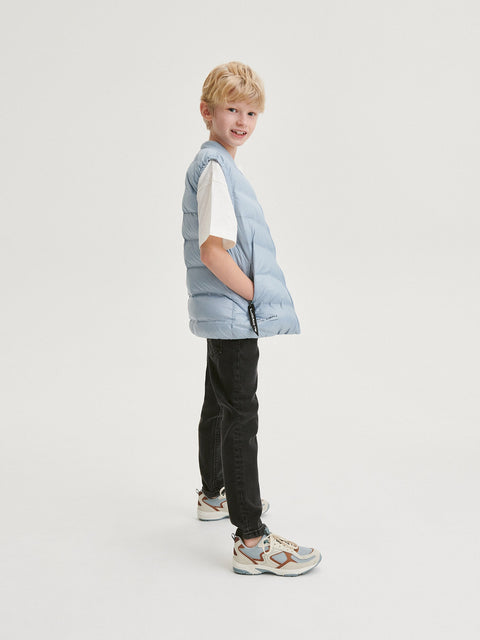 Child wearing a light blue puffer vest on a white background