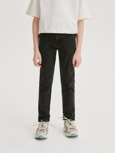 Person wearing black jeans and a white top on a plain background