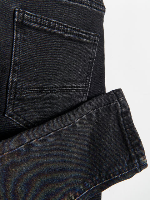 Close-up of black denim jeans with a pocket detail on a light gray background