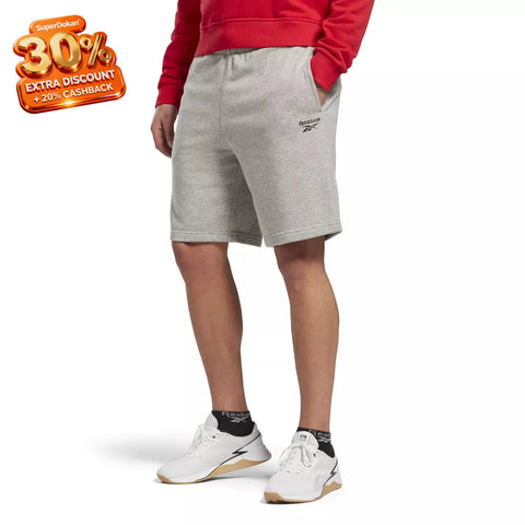 Person wearing gray shorts with a brand logo on a white background