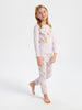Young girl wearing a white long-sleeve top and patterned pants on a white background