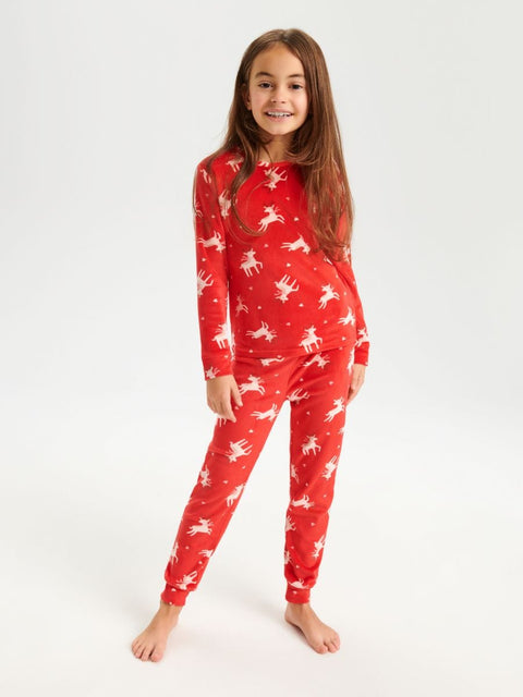 Child wearing a red pajama set with white deer pattern on a white background