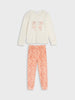Children's pajama set with cream top and pink pants with white polka dots on a light gray background