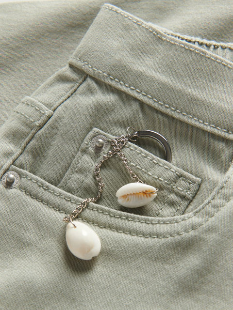 Shell charm necklace draped over a green pocket