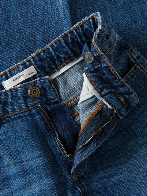 Close-up of blue denim jeans with a 'Reserved' tag.