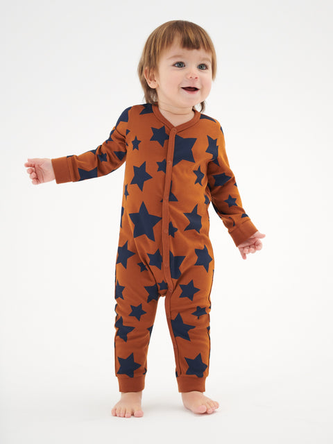 Child wearing a brown onesie with star patterns on a white background