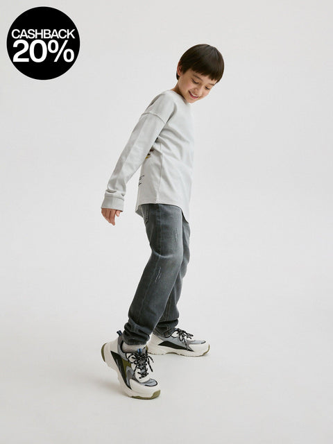Child wearing a gray sweater and jeans on a white background