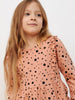 Young girl wearing a pink dress with black polka dots on a white background