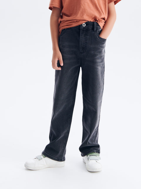 Person wearing dark jeans and a brown shirt on a white background