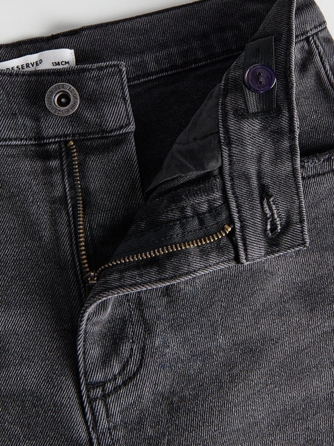 Close-up of a black denim jacket with zippers and buttons.