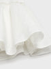 Close-up of a white ceramic bowl with ruffled edge on a light background