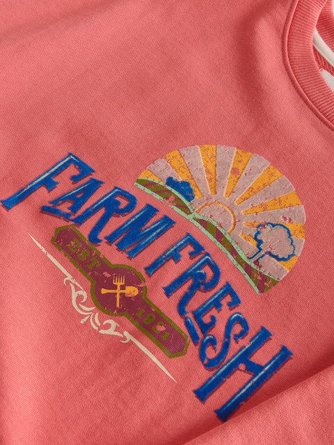 Close-up of a pink shirt with 'Farm Fresh' logo on a plain background