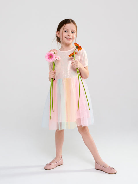 Young girl in a pastel dress holding flowers against a white background