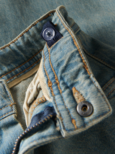 Close-up of a blue denim fabric with buttons and stitching details
