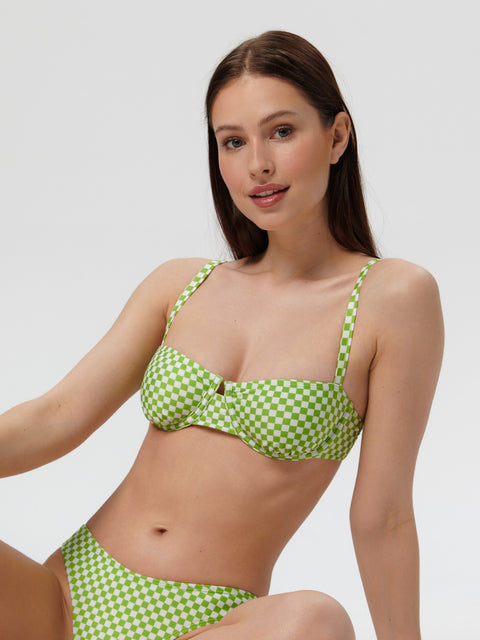 Woman wearing a green and white checkered bikini against a plain background
