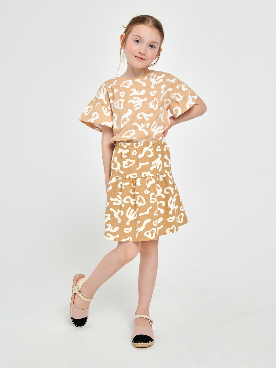 Young girl wearing a beige dress with white pattern on a white background