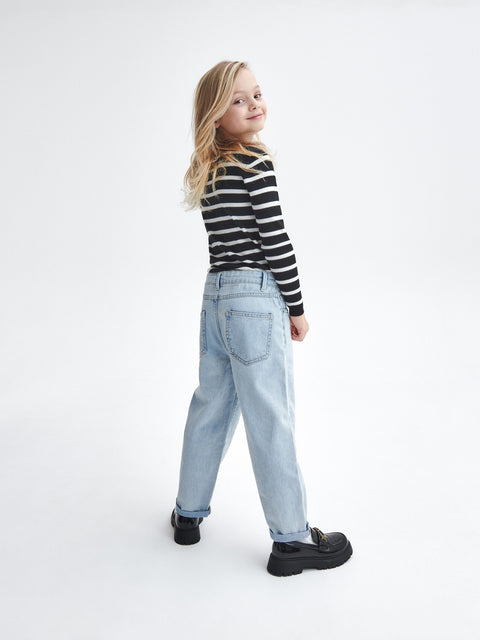 Young girl wearing a black and white striped shirt and light blue jeans on a white background