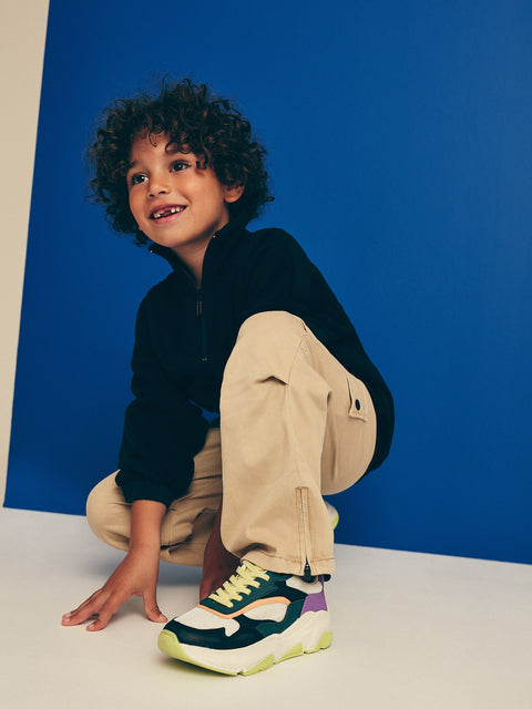 Child wearing colorful sneakers against a blue background