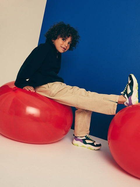 Child sitting on a red ball with a blue wall in the background