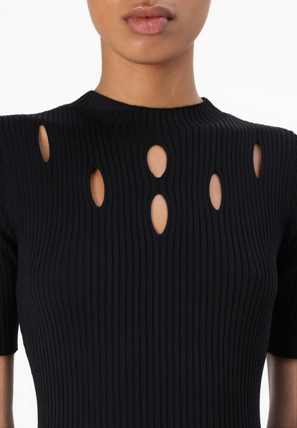 Close-up of a model wearing a black ribbed short-sleeve top with vertical cutouts on the chest.