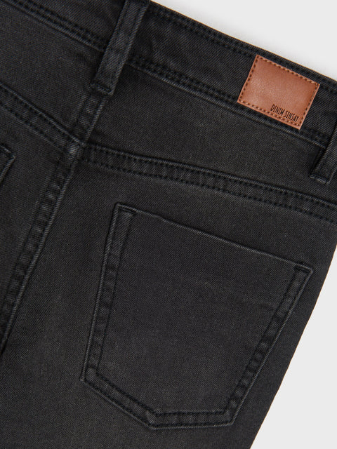 Close-up of black jeans with a brand label on a white background