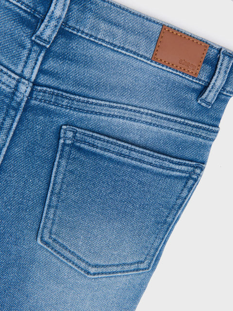 Close-up of blue denim jeans with a brown leather patch on a white background