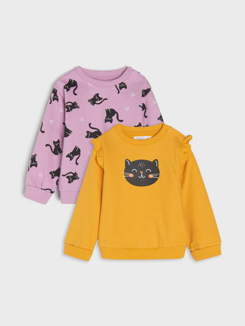 Two children's sweatshirts, one pink with black cat prints and one yellow with a black cat face, on a light gray background.