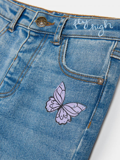 Blue denim shorts with a purple butterfly patch and 'fly high' text on a white background