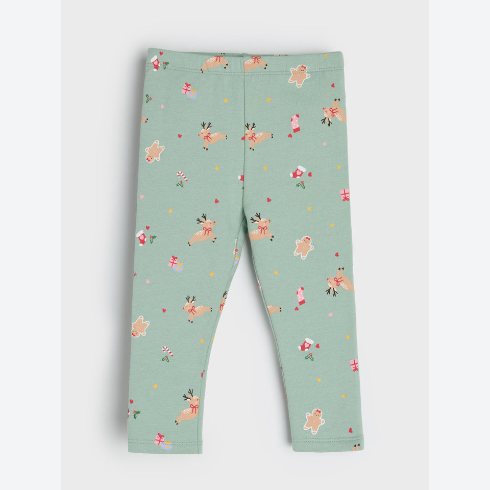 A pair of children's leggings in a light sage green color, featuring an all-over festive print of gingerbread men, reindeer, candy canes, and small red hearts.