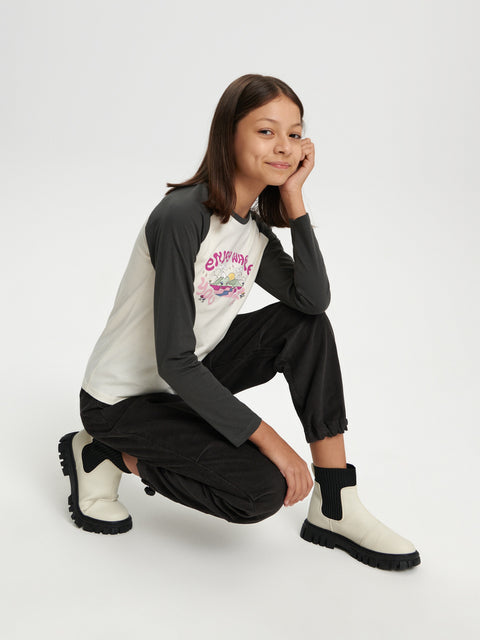 Person wearing a black and white outfit with a graphic shirt and white boots on a white background