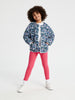 Child wearing a floral jacket and pink leggings on a white background