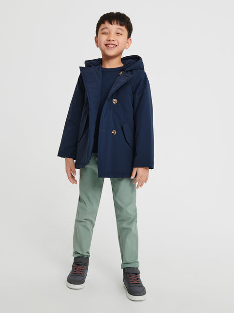 Child wearing a navy coat with a hood on a white background