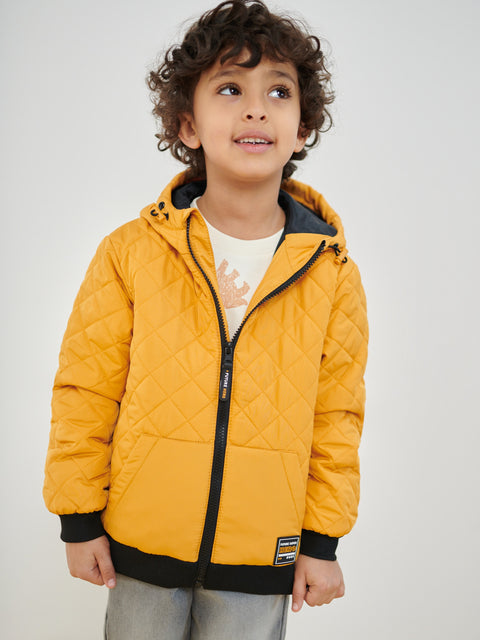 Child wearing a yellow quilted jacket against a plain background