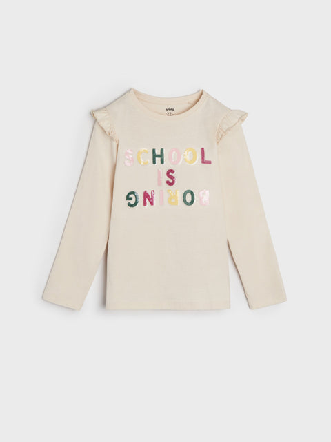 Beige long-sleeve shirt with 'SCHOOL IS NOW' text on a white background