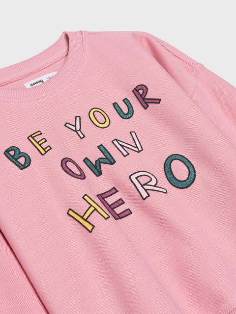 Pink sweatshirt with 'Be Your Own Hero' text in colorful letters on a white background
