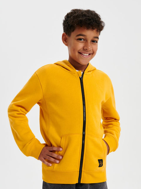 Child wearing a yellow hoodie on a white background