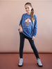 Person wearing a blue sweatshirt with a graphic design on a beige background