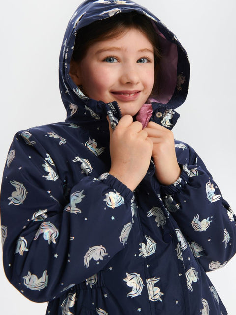 Child wearing a navy raincoat with unicorn pattern on a white background