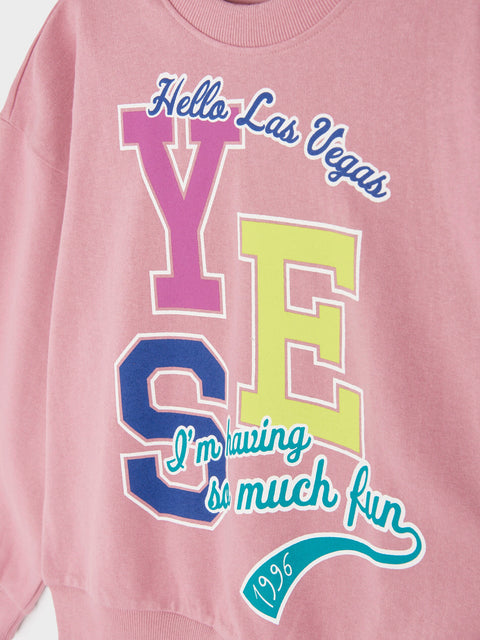Pink sweatshirt with colorful text 'Hello Las Vegas YES I'm having so much fun 1956' on a white background